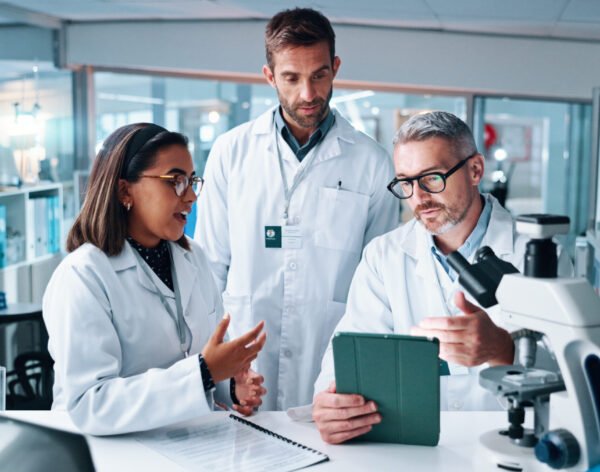 Discussion, science and tablet with people in laboratory together for breakthrough or development. Conversation, laptop and microscope with professional research team in clinical trial for discovery.